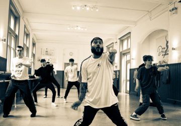 Jack Robinson, hip hop artist in a black and white photo leading young male dancers in a session