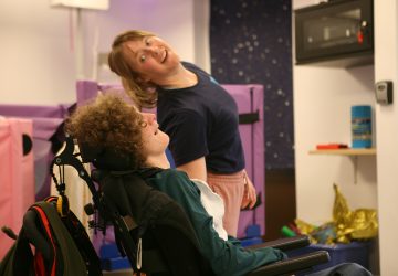 A dance artist leaning and moving towards a lady in a wheelchair