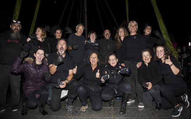 A group of volunteers all dressed in black, all facing forward with happy expressions