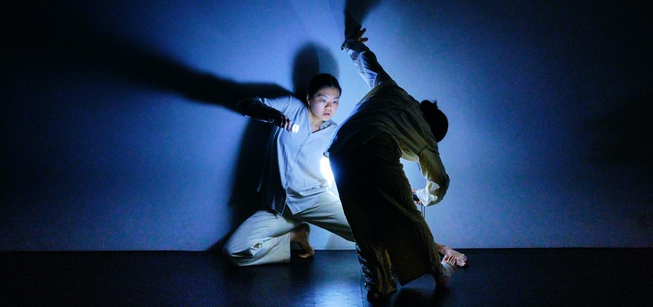 Two people dancing in the darkness with a blue spotlight.